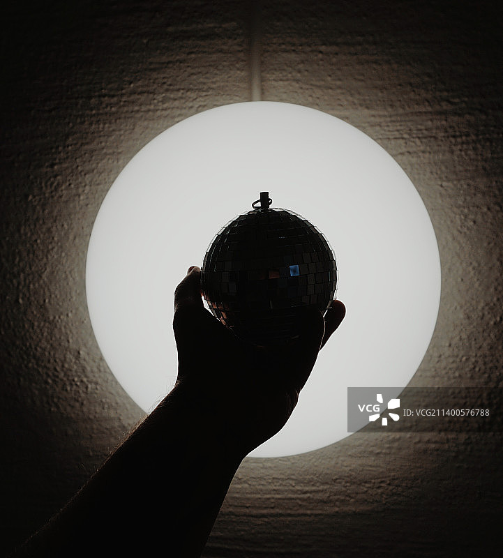 手持迪斯科球和壁灯特写图片素材