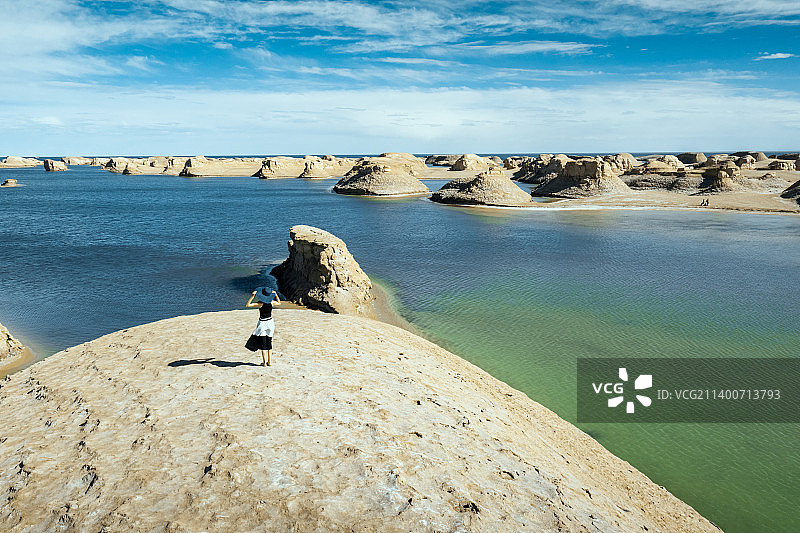 一个站在水上雅丹眺望的年轻女孩图片素材