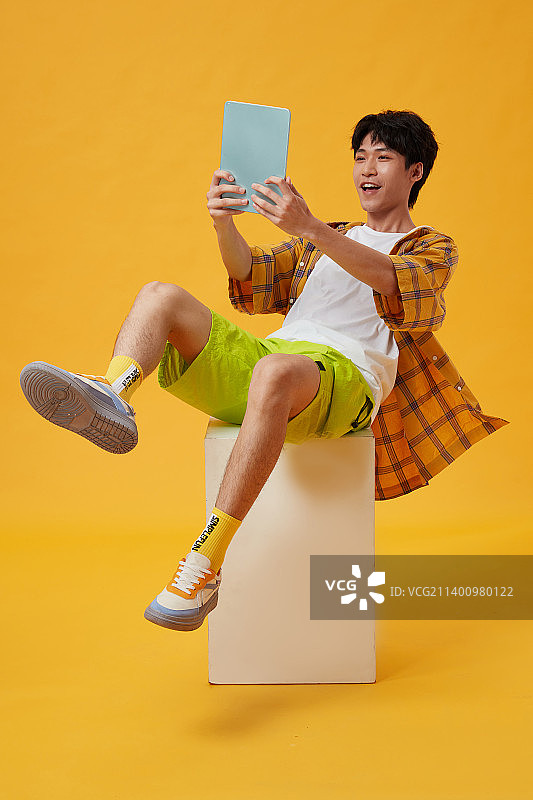 坐在木箱子上玩游戏的年轻男孩图片素材