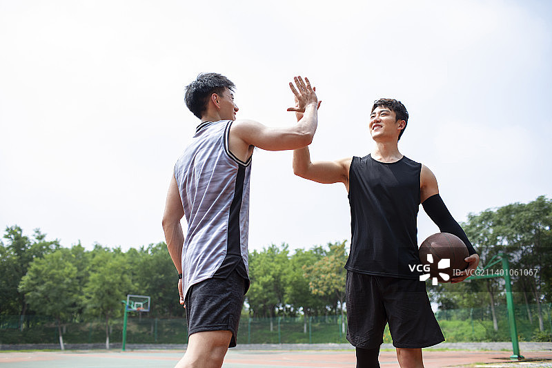 开心的年轻人在篮球场打篮球图片素材