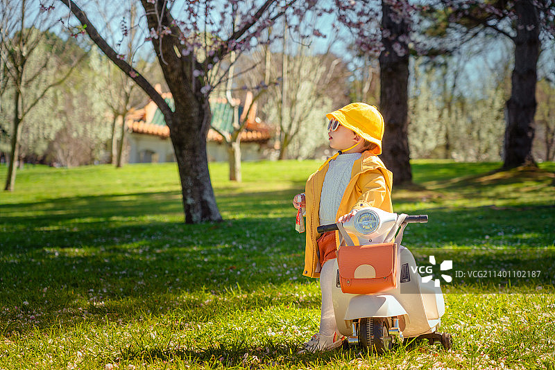 湖畔树林草坪上凹造型的黄风衣摩托车男孩图片素材