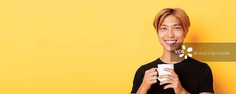 快乐满足的亚洲男子微笑，手持咖啡杯图片素材