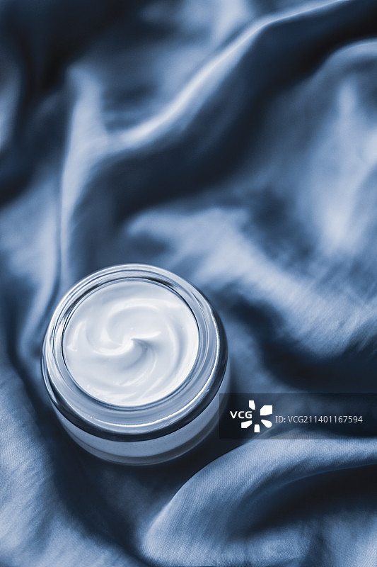 浅蓝色丝绸上的美颜霜罐子图片素材