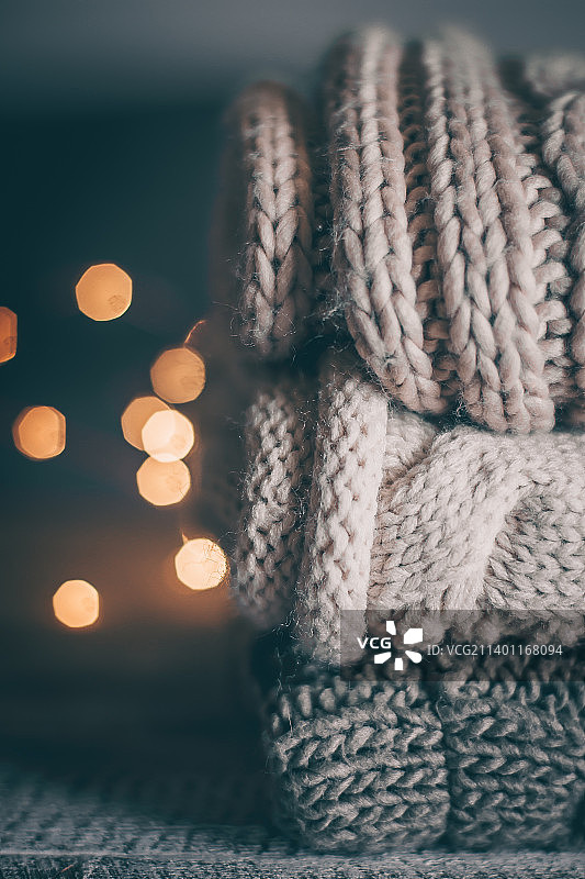 木质背景上堆叠的舒适针织毛衣和花环灯图片素材