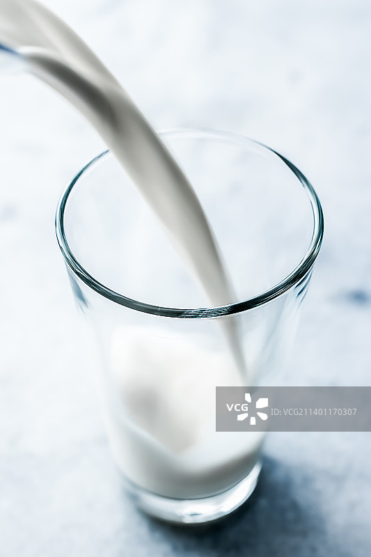世界牛奶日，将牛奶倒入大理石桌上的玻璃杯中图片素材