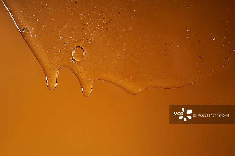 滴落在黄色背景上的沐浴露或洗发水图片素材