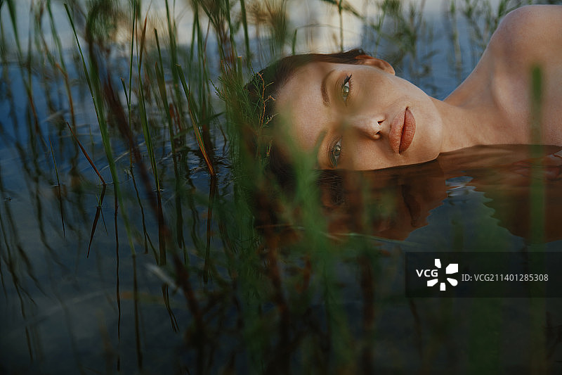 女士身着连衣裙，漂浮在海藻池塘中图片素材