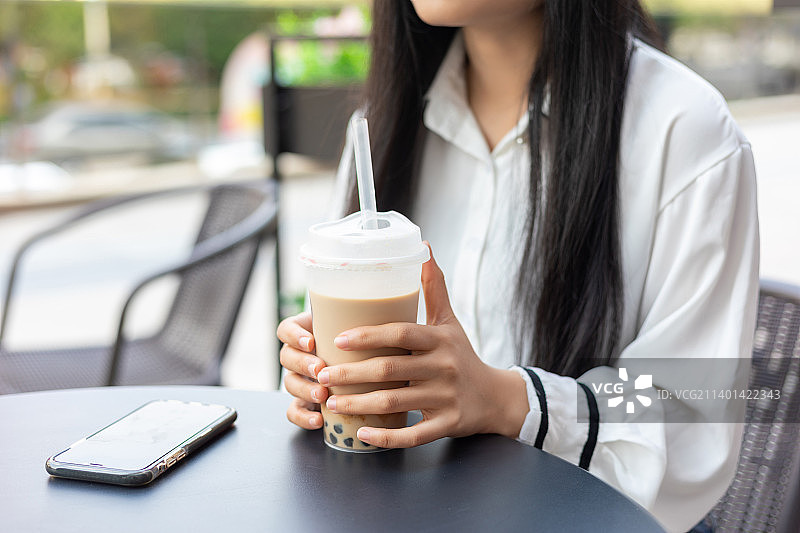 一名年轻女性在户外喝珍珠奶茶图片素材