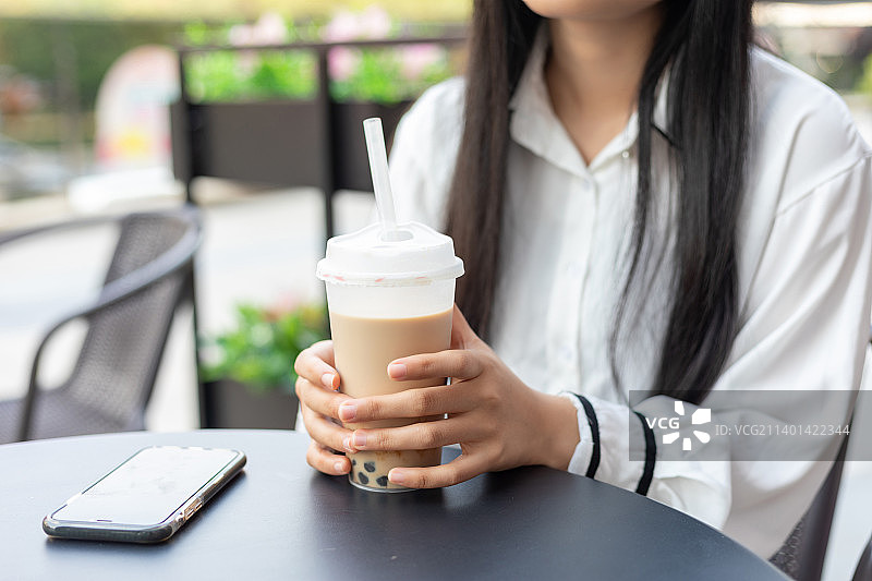 一名年轻女性在户外喝珍珠奶茶图片素材