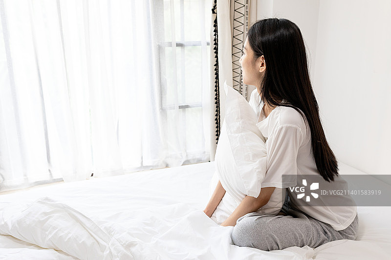 卧室内一名年轻中国女性起床图片素材