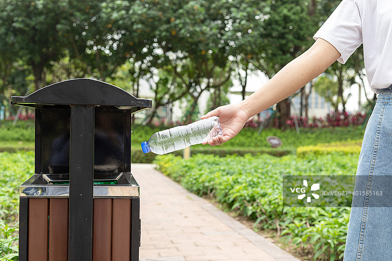 年轻女子把矿泉水瓶扔进垃圾桶里图片素材
