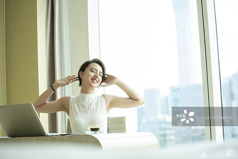 商务女子在酒店房间使用笔记本电脑工作、伸懒腰图片素材