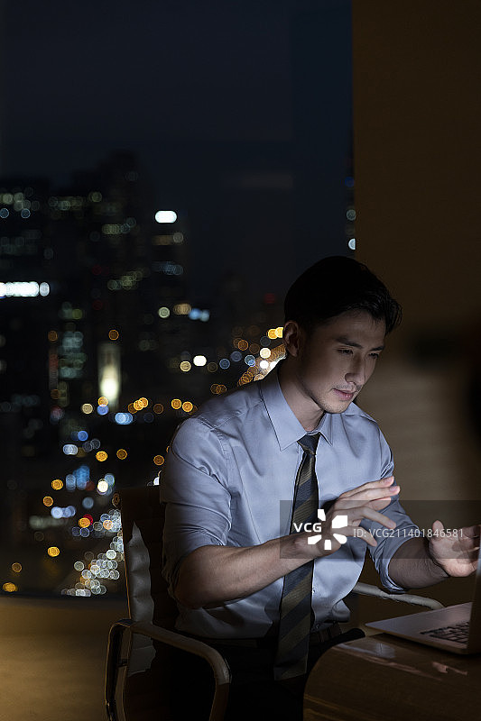 夜晚商务男子在酒店房间使用笔记本电脑视频加班图片素材