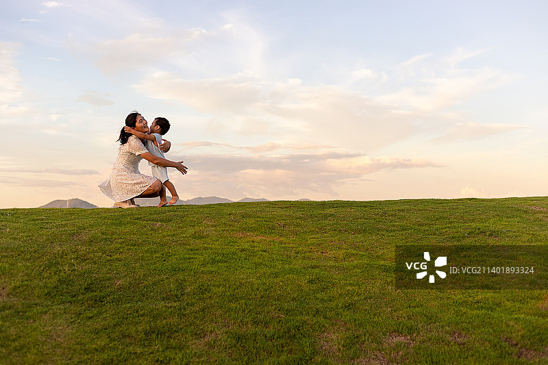 黄昏草地上一个小孩子跑向妈妈怀里图片素材