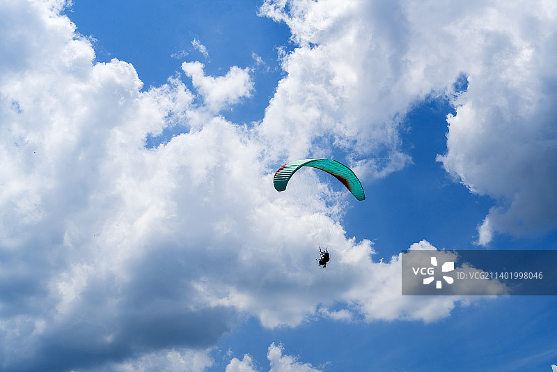 湖北利川滑翔伞飞翔在蓝天白云间图片素材