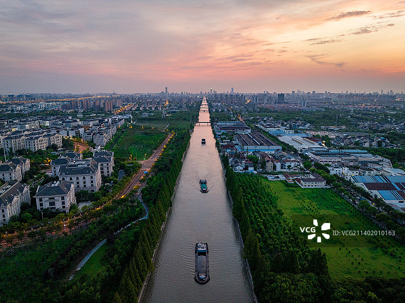 日落时分天边挂着晚霞，上海浦东笔直的运河川杨河倒影着天空，水面上船只来往非常繁忙，一座座桥横跨其上图片素材