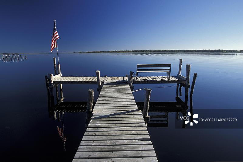 清晨的船坞和星条旗，明尼苏达州森林湖平静的倒影图片素材
