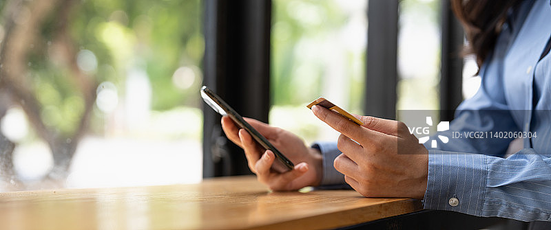 特写：女性用智能手机和信用卡进行在线支付图片素材