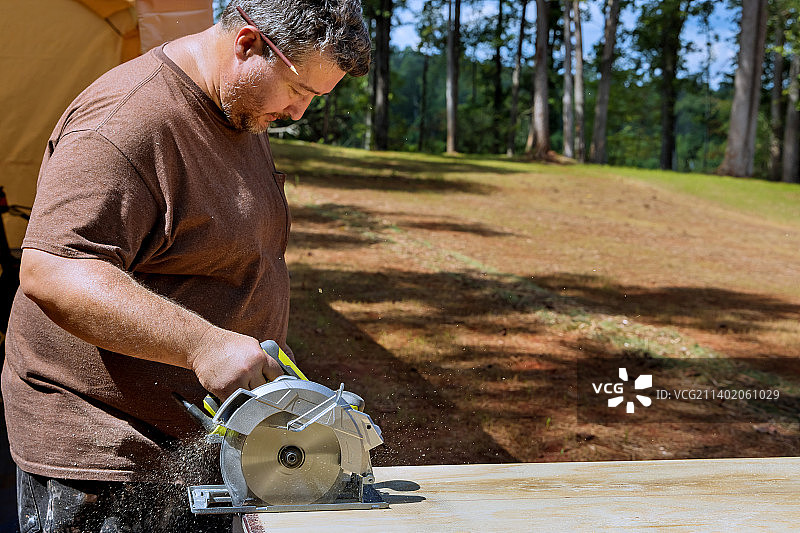 工人用手持圆锯切割胶合板图片素材