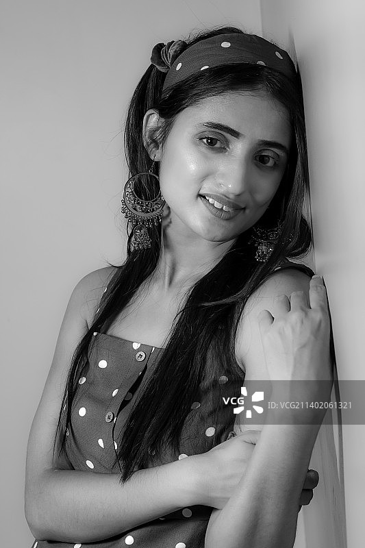 站在墙边微笑的年轻女子肖像图片素材