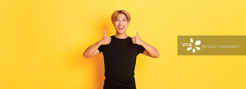 竖版：亚洲男学生竖起大拇指的满意肖像图片素材