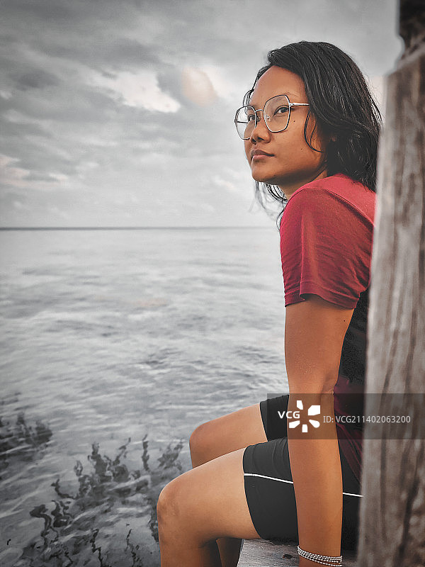 坐在海边对着天空的年轻女子 портрет，印尼卡里群爪哇图片素材