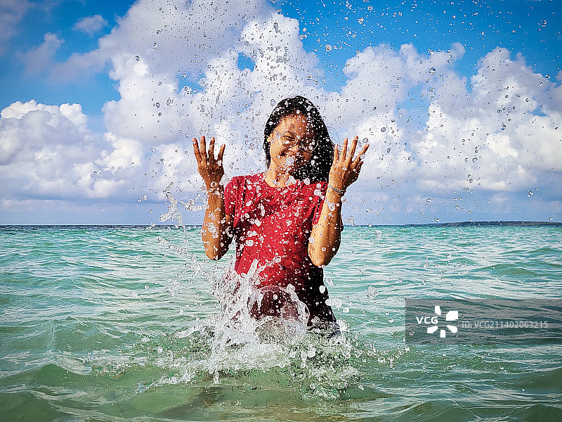 女孩在印度尼西亚卡里蒙爪哇海边戏水，背景是天空图片素材