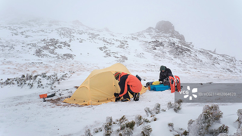 徒步旅行者在冬季山区里搭帐篷图片素材