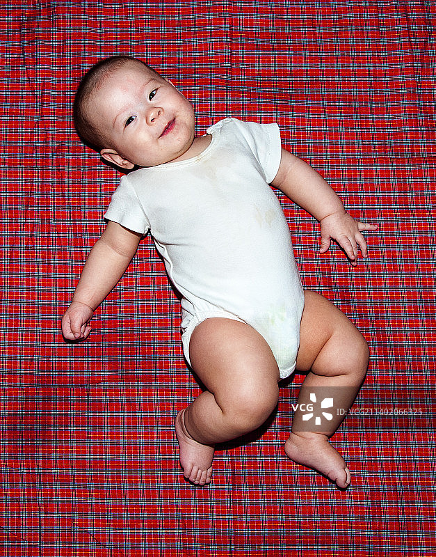 躺在红色毯子上的可爱男婴的俯视图图片素材