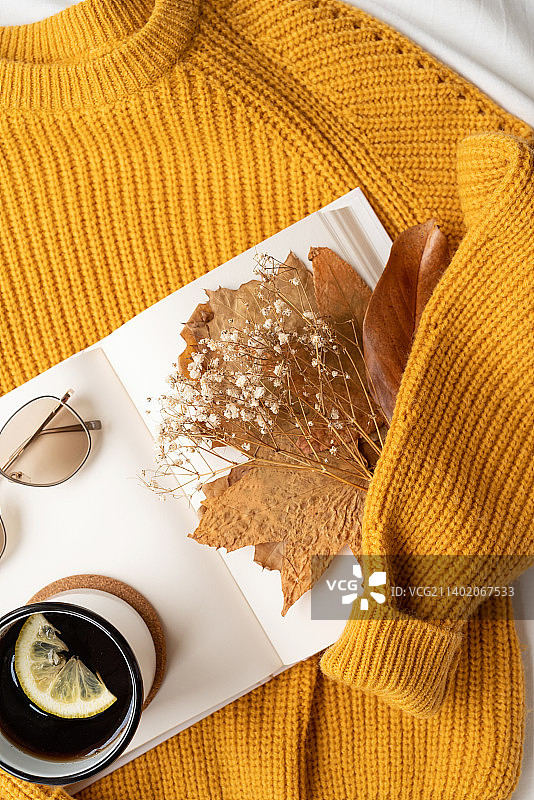 暖和的毛衣、白皮书、热茶和秋叶的舒适搭配，顶视图图片素材