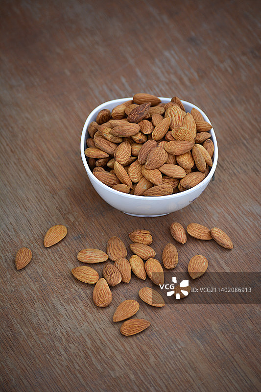 木制背景白色碗中的杏仁，印度图片素材