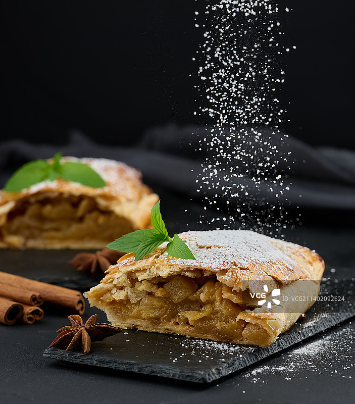 撒有糖粉的烤苹果馅卷饼，置于黑板上图片素材