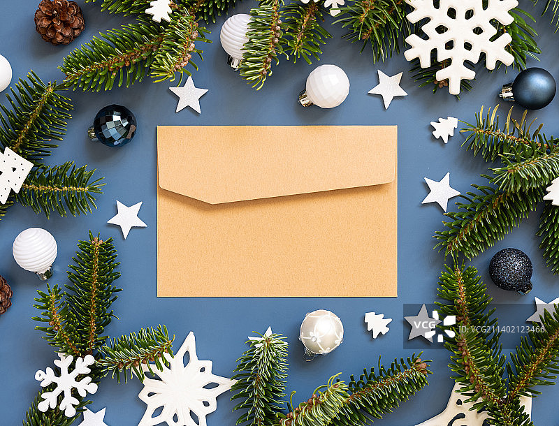 蓝色背景上手工纸信封、白色圣诞装饰品和冷杉树枝图片素材