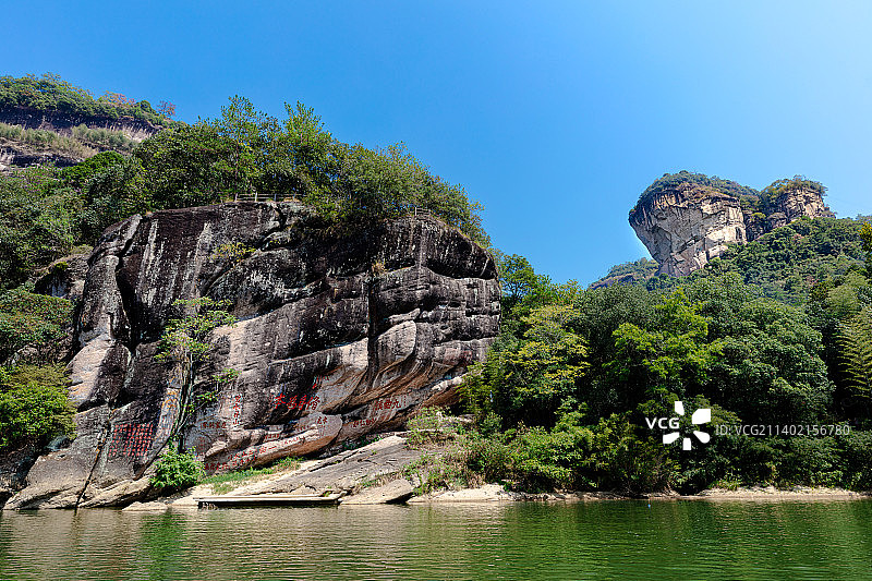 武夷山九曲溪畔水光石岩石上的摩崖石刻，古代儒学文人书有修身为本碧水丹山等题词，远处为险峻的大王峰图片素材