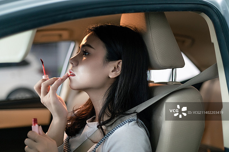 停车场里中国年轻女性在车里化妆图片素材