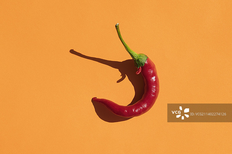 黄色背景下的红色辣椒，硬阴影图片素材