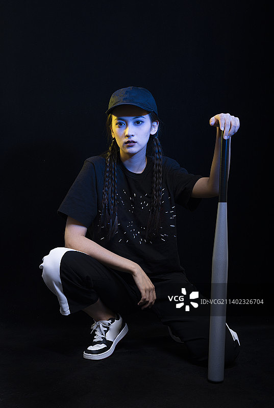 黑色背景下拿着棒球棍的冷酷女孩图片素材