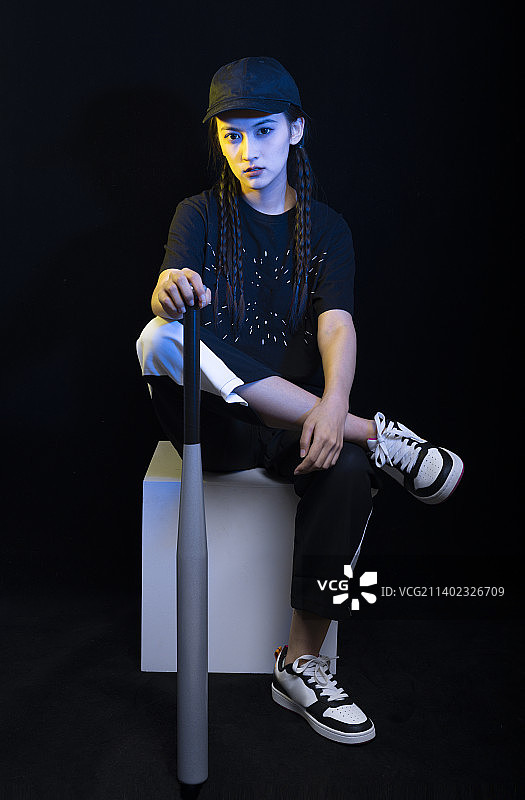 黑色背景下拿着棒球棍的冷酷女孩图片素材