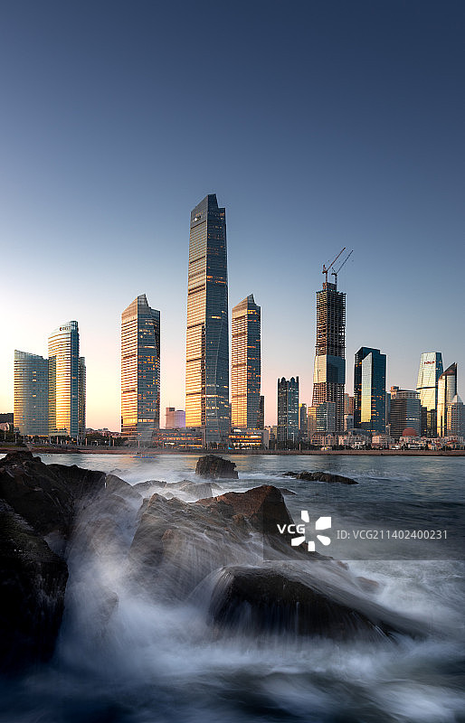 光影青岛 选取礁石作为前景，0.5s的快门速度记录下丝绸般的海面与夜幕时分的青岛城市建筑群。图片素材