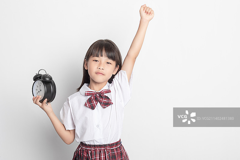 一个中国小学生小女孩手拿着一个闹钟图片素材