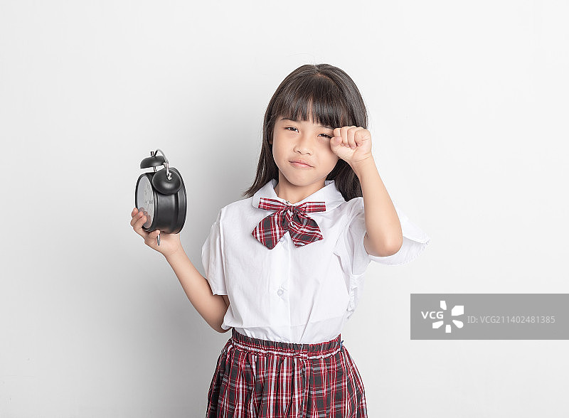 一个中国小学生小女孩手拿着一个闹钟图片素材