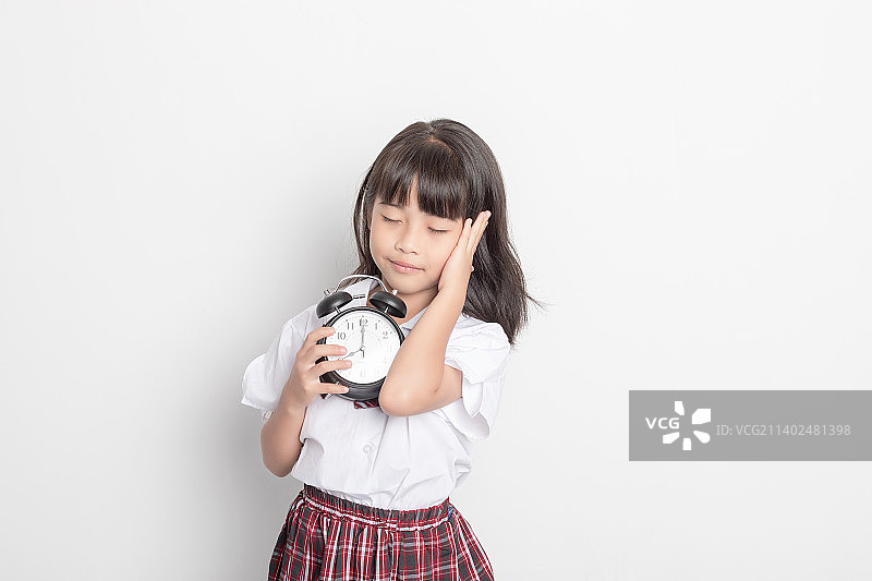 一个中国小学生小女孩手拿着一个闹钟图片素材