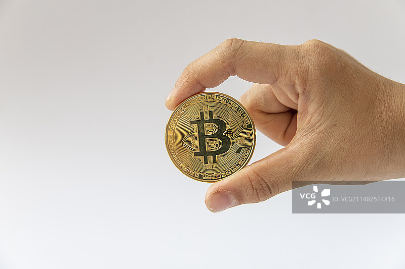 手里拿着一枚比特币图片素材