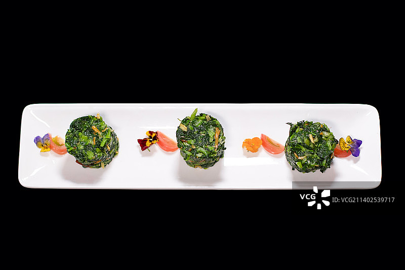 黑色背景下盘子里青菜菜团食物的特写镜头图片素材