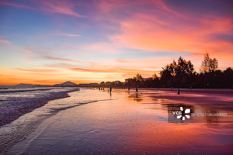 海南三亚椰梦长廊沐浴在夕阳余晖下的游客、市民图片素材