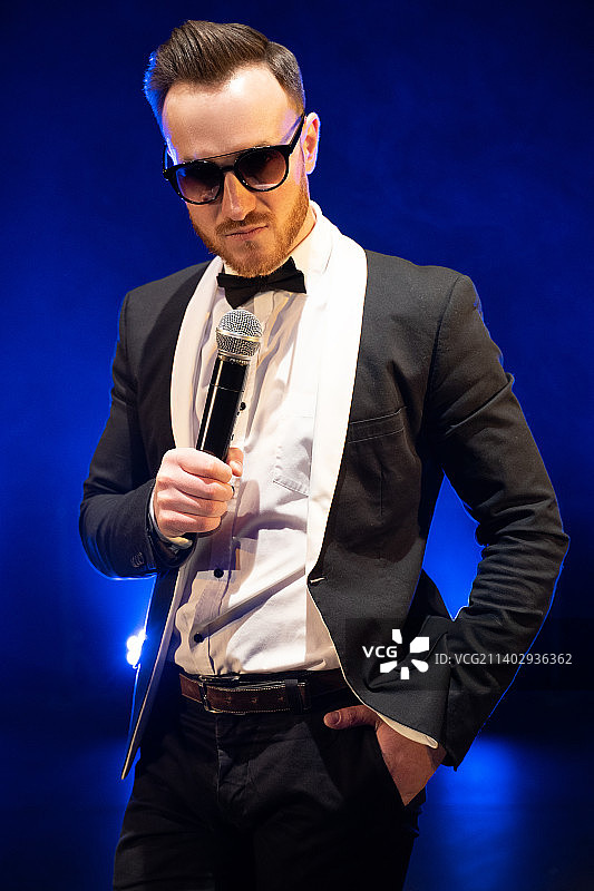 站在蓝色背景前唱歌的男人图片素材