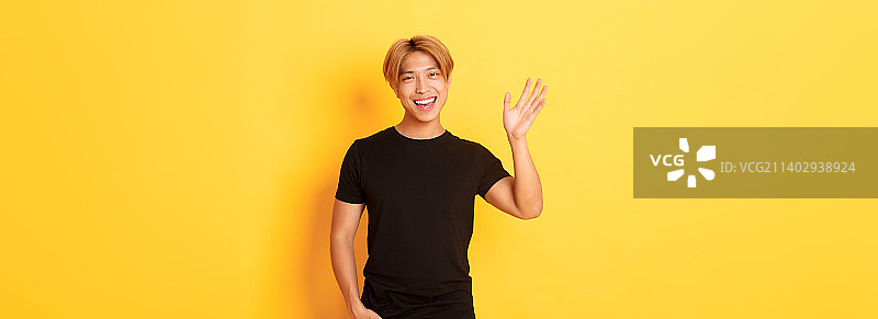 身穿黑色服装的友善亚洲男子肖像，挥手致意图片素材