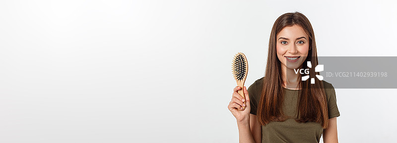 快乐的年轻女人在白色背景上梳理她健康的长发图片素材