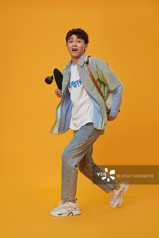 背着书包手拿滑板的年轻男生图片素材