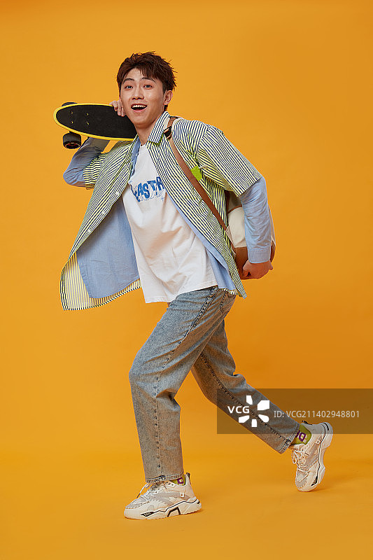 背着书包手拿滑板的年轻男生图片素材